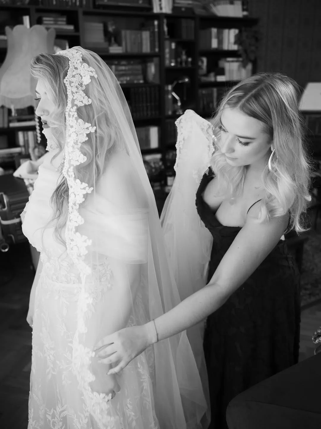 A friend helps the bride with her veil and dress during the morning preparations